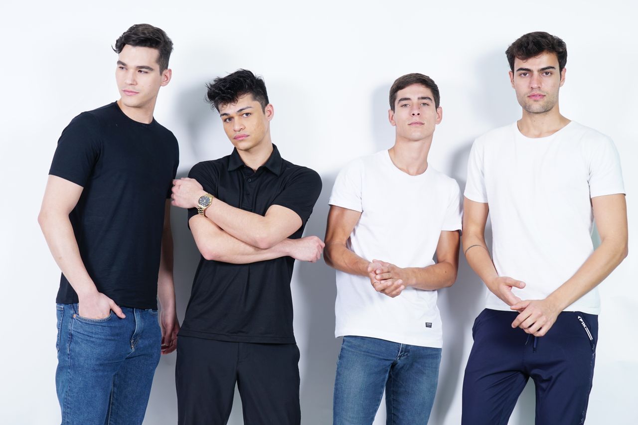 services-04 Group of four young men in casual outfits posing in studio with white background.