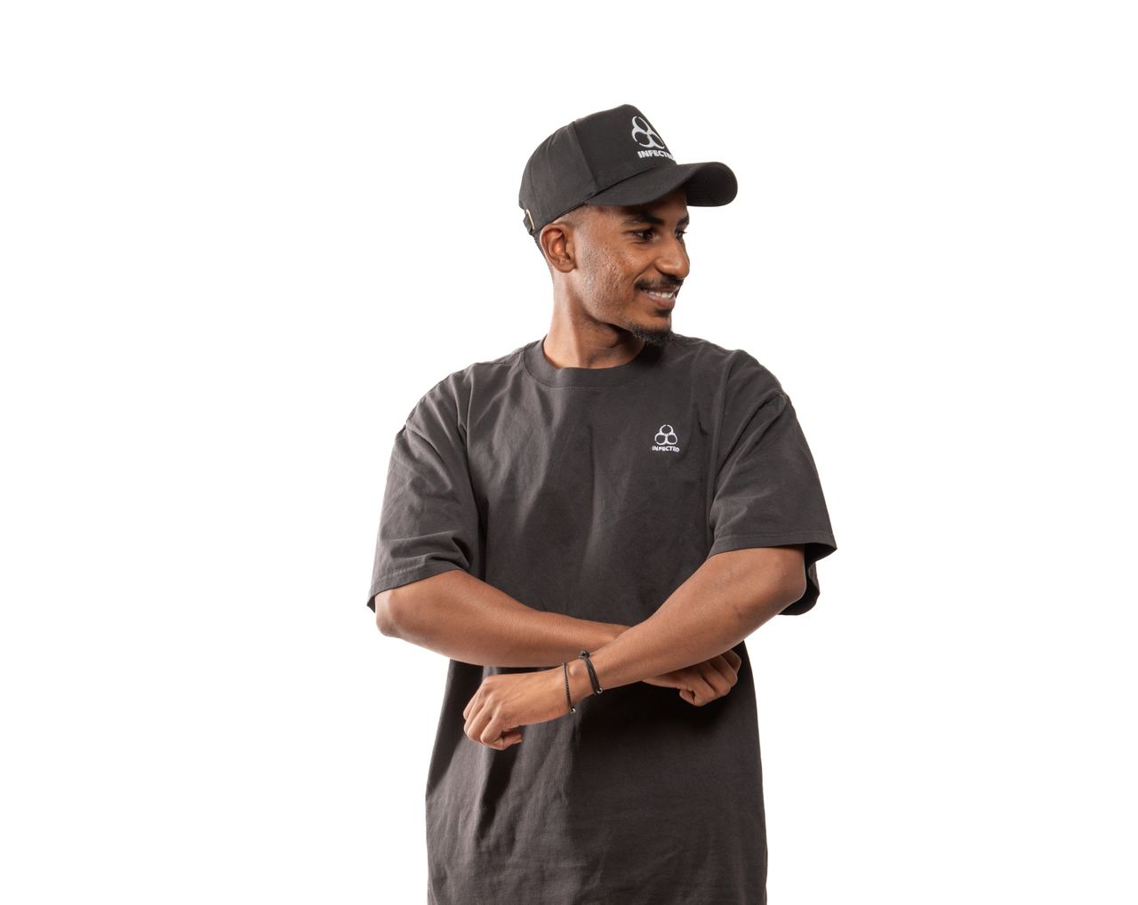 about-us Smiling man in a black T-shirt and cap with folded arms.
